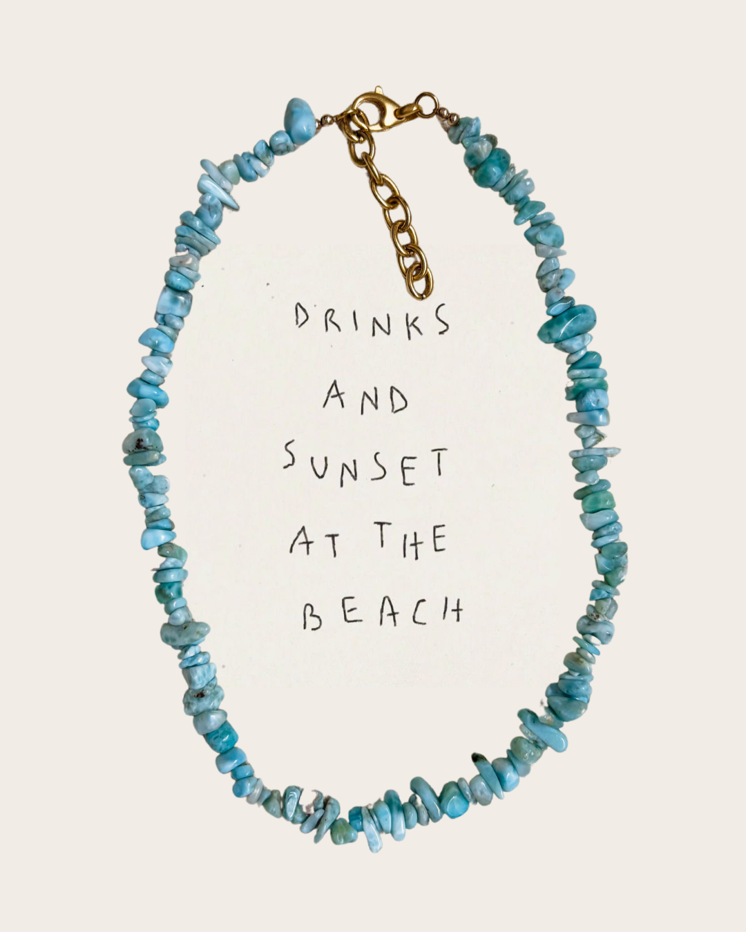 A bold Larimar chip bead necklace with a gold lobster clasp and extender chain is styled around handwritten text that reads “drinks and sunset at the beach.” The vibrant blue gemstones evoke tropical waters and relaxed summer evenings, capturing the essence of beachy, coastal style. This handmade necklace from Soul Wave Beach Co is part of the Ocean Heritage collection, celebrating seaside nostalgia, island energy, and effortless, sun-drenched jewelry design.