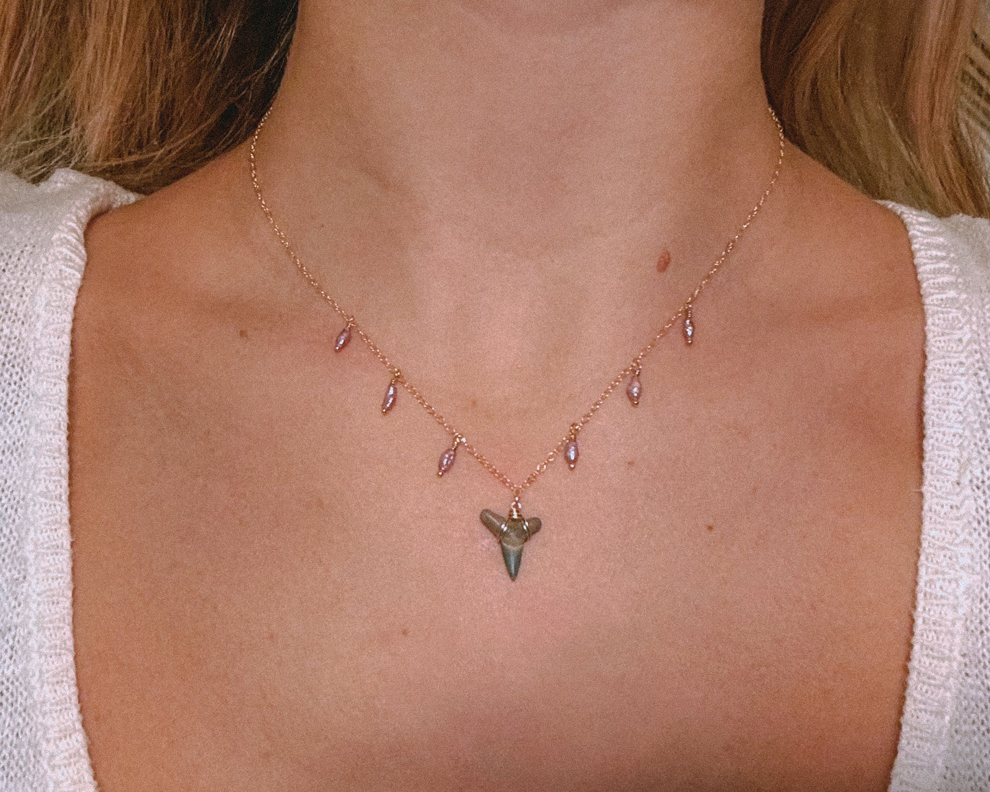 Close-up of a woman wearing a 14k gold filled shark tooth necklace with antique purple rice pearls, styled as a dainty coastal choker. The fossilized shark tooth is centered on a delicate gold chain with pearl accents, showcasing a beachy, boho aesthetic perfect for ocean lovers and summer jewelry collections.