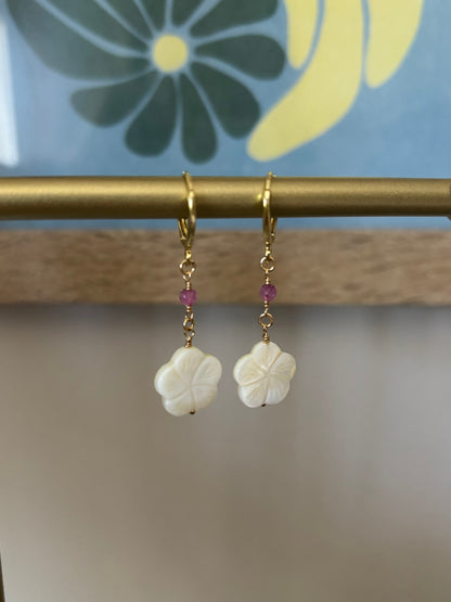 Close-up of Hibiscus Dangle Earrings featuring white carved shell flowers, black shark teeth, and pink gemstones. Suspended on 18k gold-plated hooks with 14k gold-filled wire. Ocean and flower-inspired earrings perfect for summer looks, beach brides, or tropical escapes. Part of Soul Wave Beach Co.’s handcrafted coastal jewelry collection.