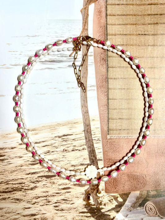Necklace made with freshwater pearls and bright pink seed beads, laid on a sandy beach backdrop with towel and ocean view. Features 18k gold-plated clasp and extender chain. Handmade by Soul Wave Beach Co, this coastal-inspired piece adds a bold pop of color with organic pearl texture—perfect for beachy, boho, or tropical summer outfits.